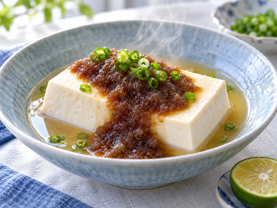 温かい豆腐に玉ねぎ入りポン酢をかけた湯豆腐の調理イメージ(AI生成)