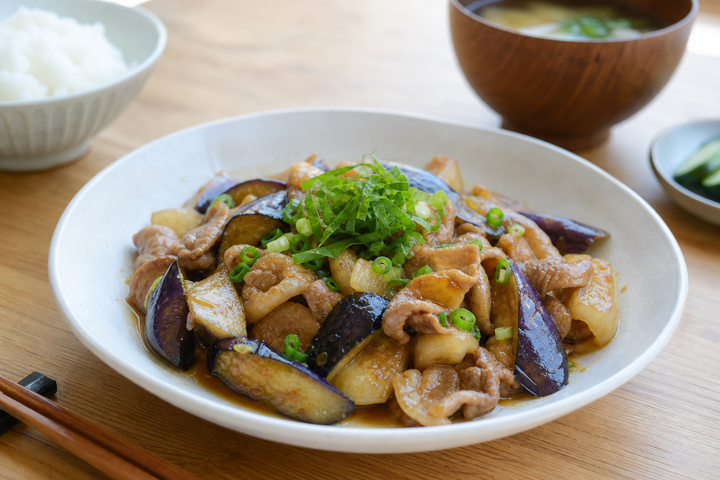 自然光の食卓に置いた豚バラとなすのさっぱり炒め